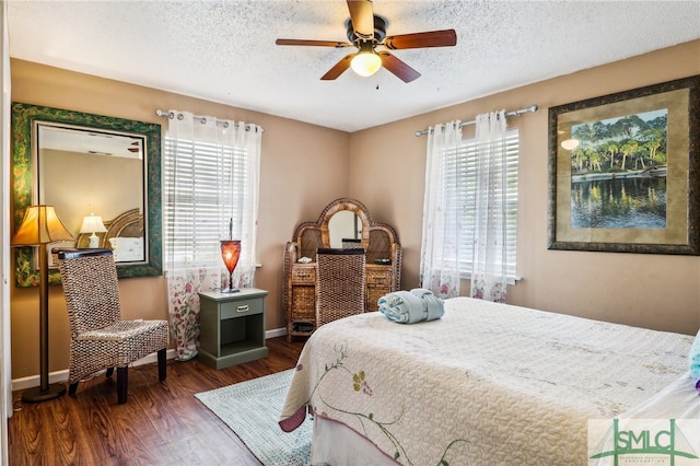 bedroom featuring multiple windows, ceiling fan, dark wood-type flooring, and a textured ceiling