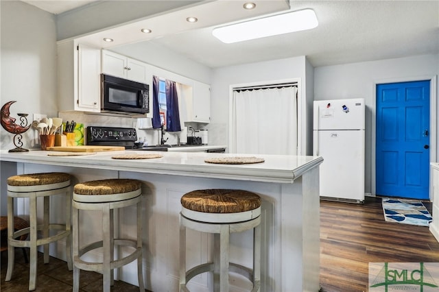 kitchen with black appliances, dark hardwood / wood-style floors, white cabinetry, and kitchen peninsula