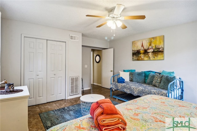 bedroom featuring ceiling fan, a closet, dark tile patterned floors, and a textured ceiling