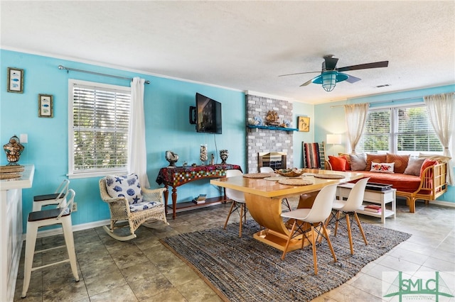 dining area featuring ceiling fan, a textured ceiling, and a brick fireplace