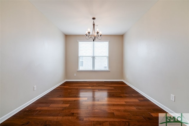 empty room with dark hardwood / wood-style flooring and an inviting chandelier