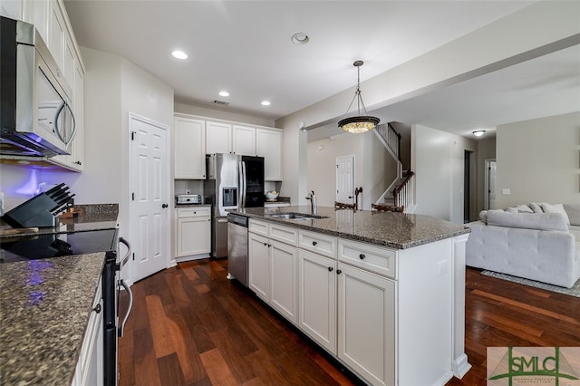 kitchen with dark hardwood / wood-style floors, white cabinetry, a kitchen island with sink, and appliances with stainless steel finishes