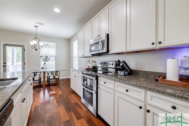 kitchen featuring dark stone countertops, white cabinets, dark wood-type flooring, and appliances with stainless steel finishes