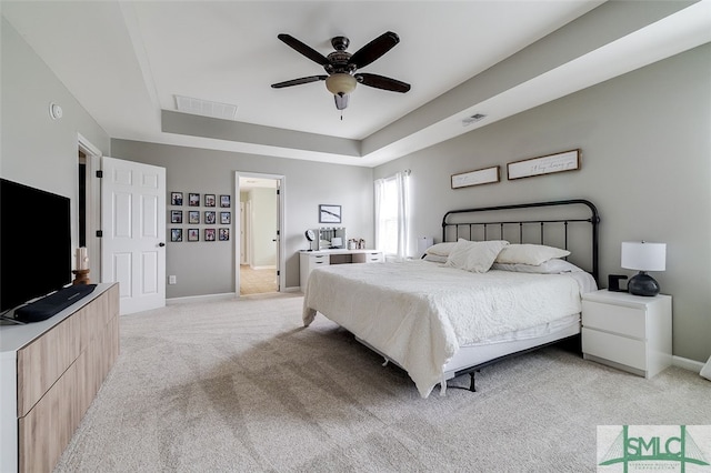 carpeted bedroom featuring a tray ceiling and ceiling fan