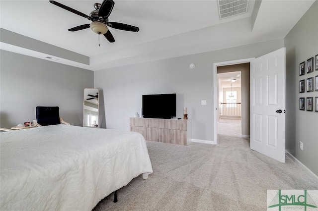 carpeted bedroom featuring ceiling fan and a raised ceiling