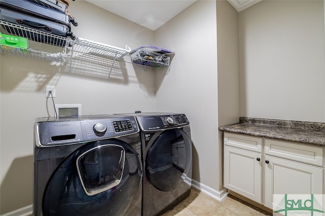 clothes washing area with light tile patterned flooring, cabinets, and washing machine and clothes dryer