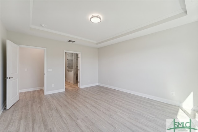 unfurnished bedroom with a raised ceiling and light wood-type flooring