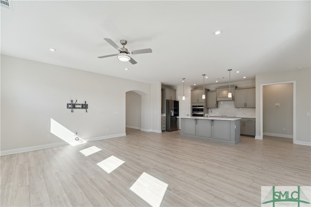 unfurnished living room featuring ceiling fan, light hardwood / wood-style floors, and sink