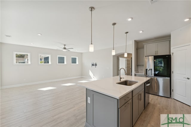 kitchen with sink, hanging light fixtures, stainless steel appliances, light hardwood / wood-style floors, and gray cabinets