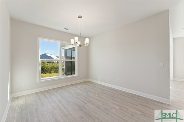 unfurnished room featuring a chandelier and light hardwood / wood-style floors