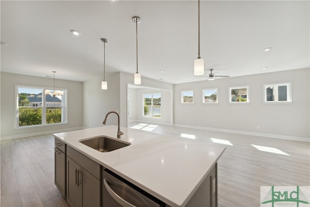 kitchen with dishwasher, light wood-type flooring, sink, and decorative light fixtures