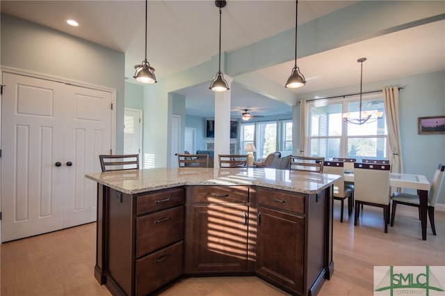 kitchen with light hardwood / wood-style floors, ceiling fan, a kitchen island, and dark brown cabinetry