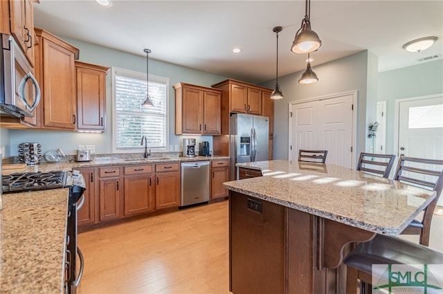 kitchen featuring a breakfast bar, sink, stainless steel appliances, and light wood-type flooring