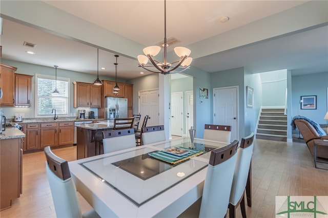 dining room with light hardwood / wood-style floors, an inviting chandelier, and sink