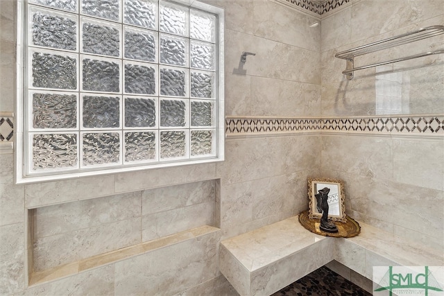 bathroom featuring a tile shower and tile walls