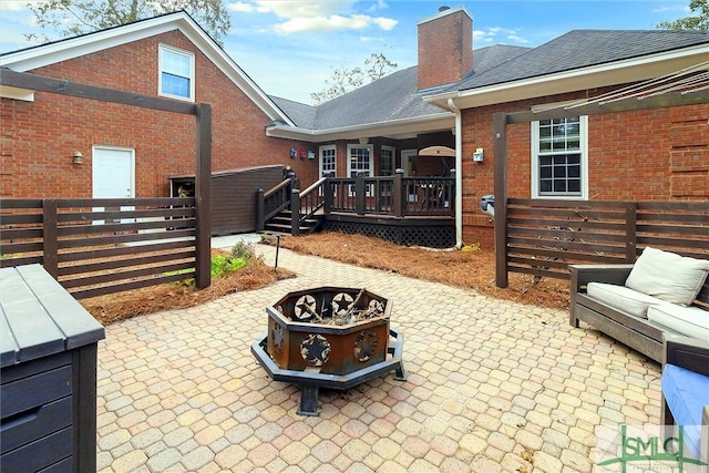 view of patio / terrace with a wooden deck and an outdoor living space with a fire pit