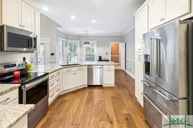 kitchen featuring appliances with stainless steel finishes, light wood-type flooring, crown molding, sink, and decorative light fixtures