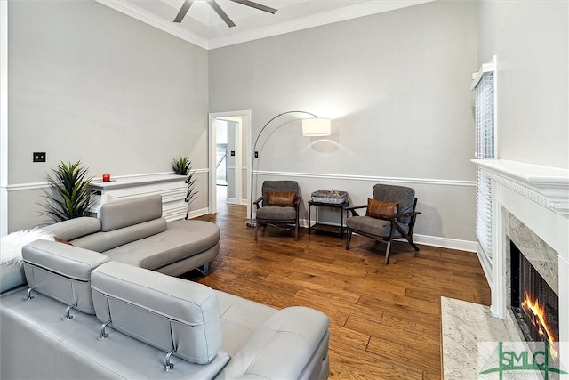 living room featuring crown molding, a high end fireplace, wood-type flooring, and ceiling fan