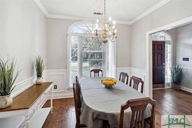 dining space with crown molding, dark wood-type flooring, and an inviting chandelier