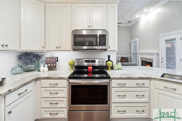 kitchen featuring light stone countertops, white cabinetry, ornamental molding, and appliances with stainless steel finishes