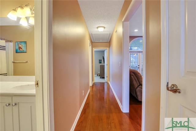 hall featuring a textured ceiling, sink, and dark hardwood / wood-style floors