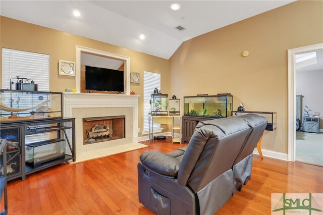 living room with a fireplace, hardwood / wood-style floors, and lofted ceiling