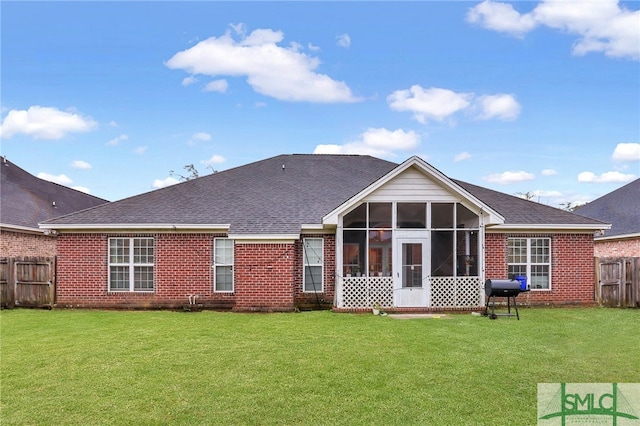 rear view of property with a yard and a sunroom