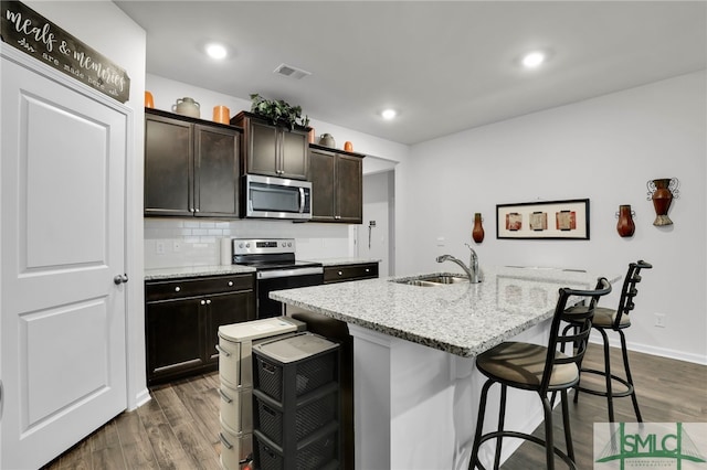 kitchen featuring appliances with stainless steel finishes, a kitchen breakfast bar, sink, dark hardwood / wood-style floors, and an island with sink