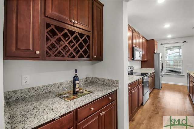 kitchen featuring light stone countertops, appliances with stainless steel finishes, and light hardwood / wood-style flooring