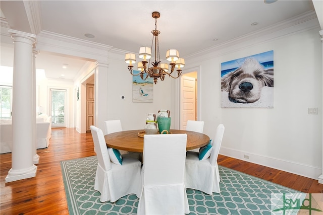 dining area with hardwood / wood-style flooring, ornate columns, ornamental molding, and an inviting chandelier