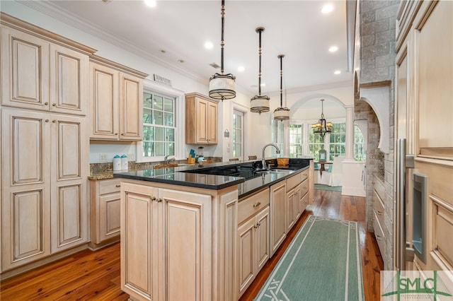 kitchen with a wealth of natural light, decorative light fixtures, a kitchen island with sink, and dark wood-type flooring