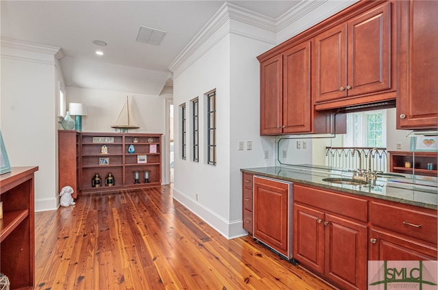 kitchen with hardwood / wood-style floors, ornamental molding, and dark stone counters