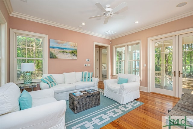 living room with ceiling fan, french doors, ornamental molding, and light wood-type flooring