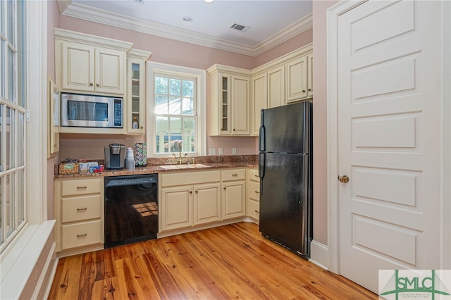 kitchen featuring cream cabinetry, light hardwood / wood-style flooring, ornamental molding, and black appliances