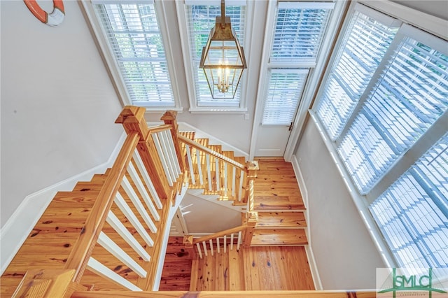 staircase with hardwood / wood-style floors and a chandelier