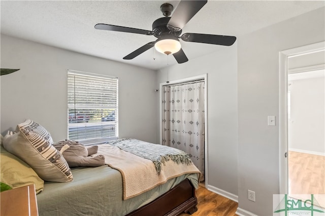 bedroom with wood-type flooring, a textured ceiling, a closet, and ceiling fan