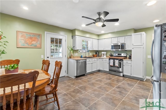 kitchen featuring dark tile patterned flooring, sink, ceiling fan, appliances with stainless steel finishes, and white cabinetry