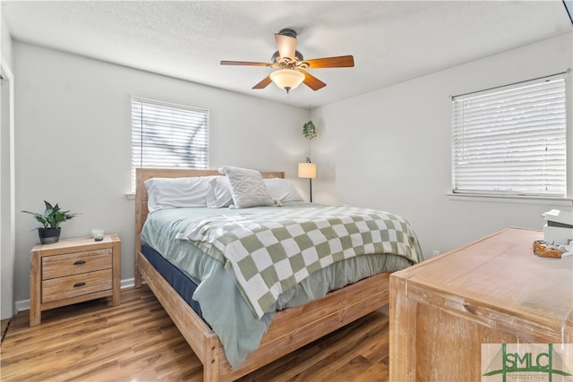 bedroom with wood-type flooring, a textured ceiling, and ceiling fan