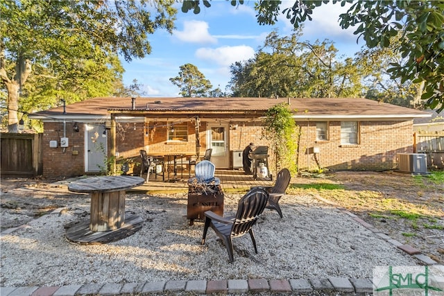 back of property with cooling unit, an outdoor fire pit, and a patio