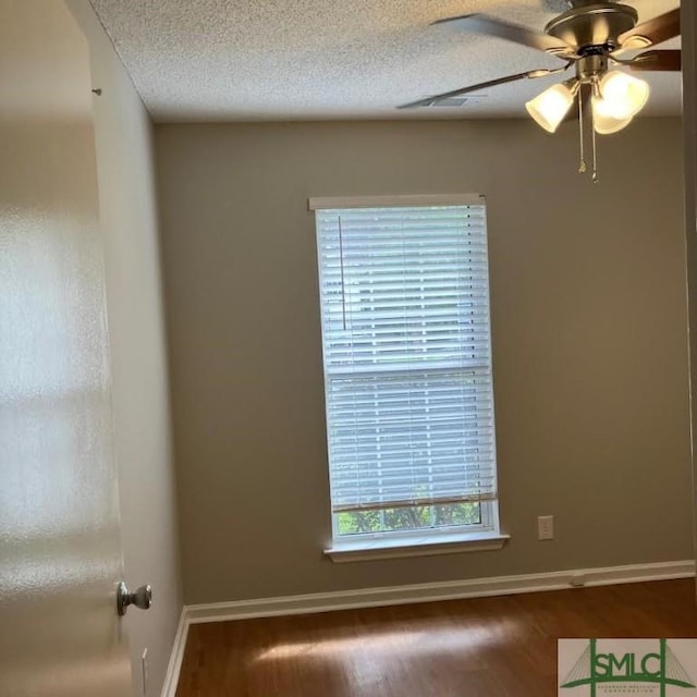 empty room with dark hardwood / wood-style flooring, ceiling fan, and a textured ceiling