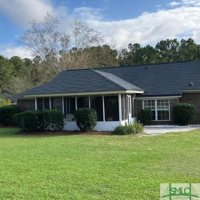 rear view of property with a sunroom and a lawn