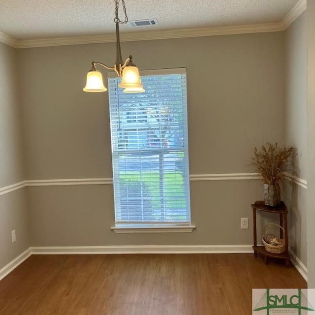 unfurnished dining area featuring an inviting chandelier, hardwood / wood-style floors, crown molding, and a textured ceiling