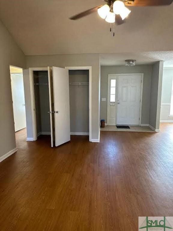 unfurnished bedroom featuring multiple closets, ceiling fan, and hardwood / wood-style floors