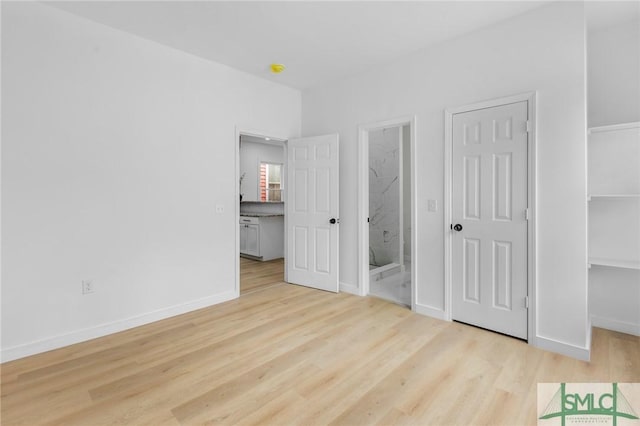 unfurnished bedroom featuring ensuite bathroom and light wood-type flooring