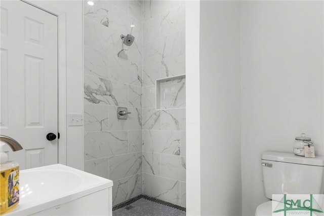 bathroom featuring vanity, toilet, and tiled shower