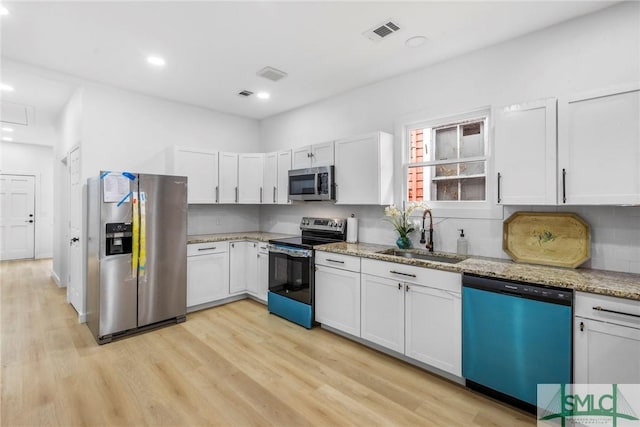 kitchen with white cabinetry, sink, stainless steel appliances, and light stone counters