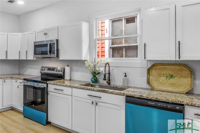 kitchen featuring white cabinetry, sink, light stone counters, and appliances with stainless steel finishes