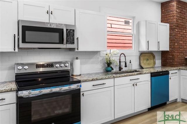 kitchen featuring white cabinets, stainless steel appliances, light stone countertops, and sink