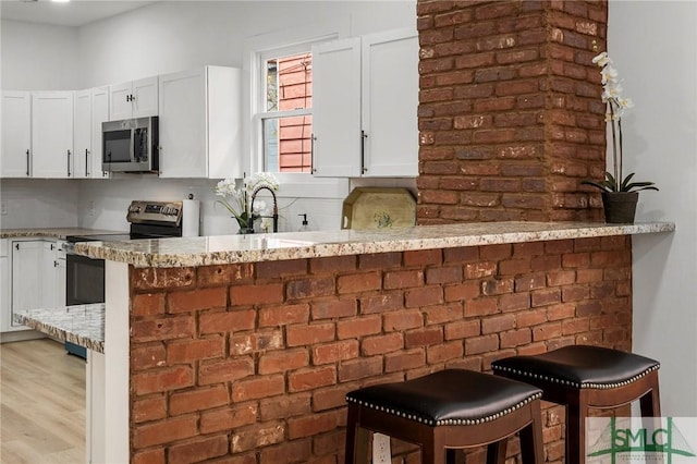 kitchen featuring a breakfast bar, stainless steel appliances, and white cabinetry