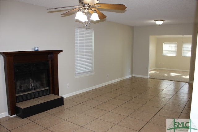 unfurnished living room with light tile patterned floors, ceiling fan, and a tiled fireplace